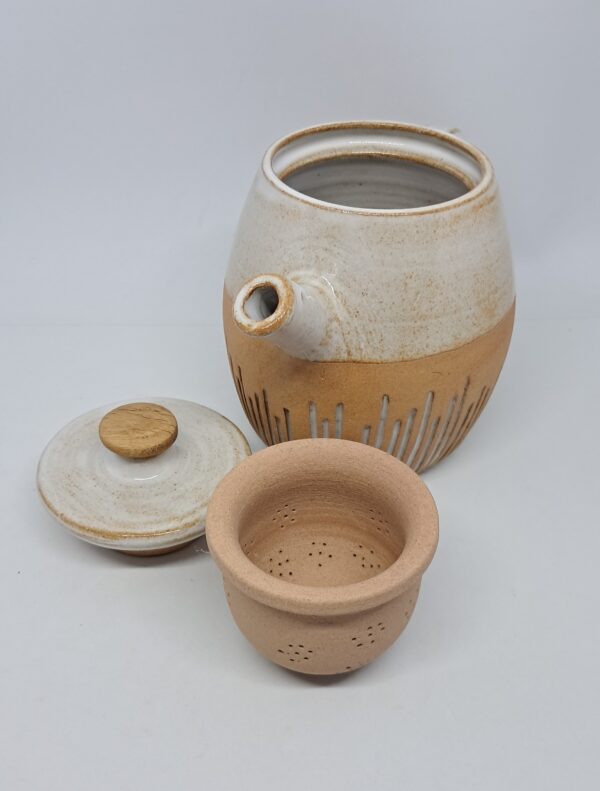 Théière ouverte, couvercle à bouton en bois clair et panier infuseur en grès roux.