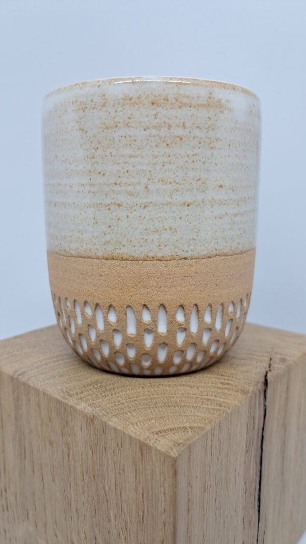 Tasse blanc brillant et grès roux sur présentoir en bois.