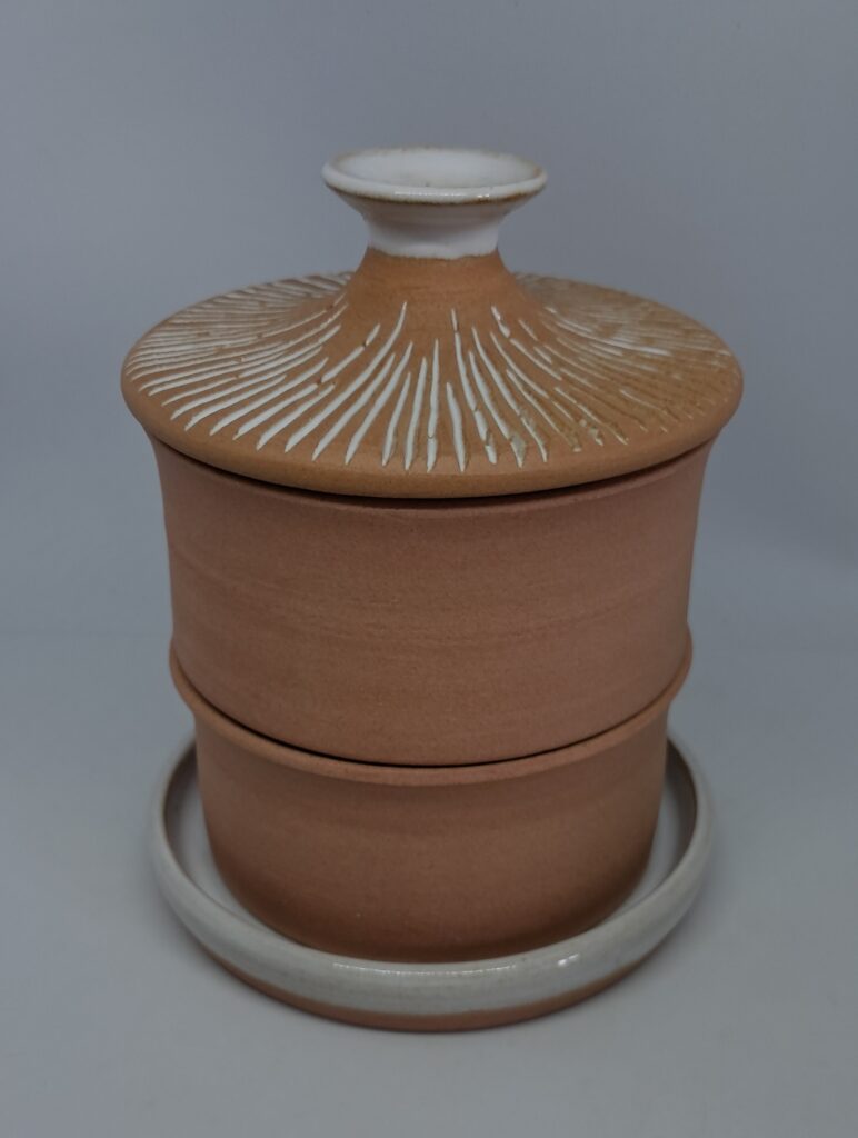 Germoir blanc brillant, composé d'une coupelle de rétention émaillée, deux bacs de germination en grès roux et d'un couvercle décoré.
