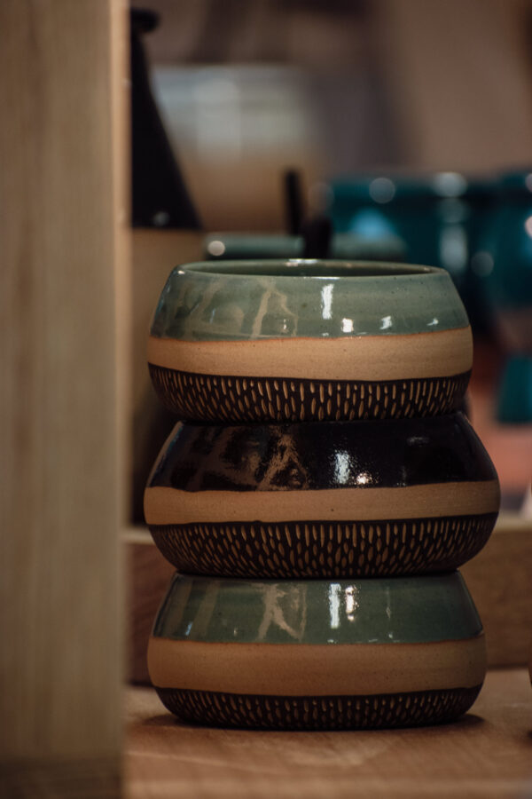 Trois tasses / bol de la même collection empilées, 2 bleues et 1 noire.