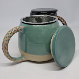 Mug tisanière bleu vert, présenté ouvert. Grès beige émaillé, anse décorée.