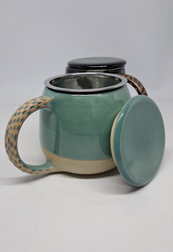 Mug tisanière bleu vert, présenté ouvert. Grès beige émaillé, anse décorée.