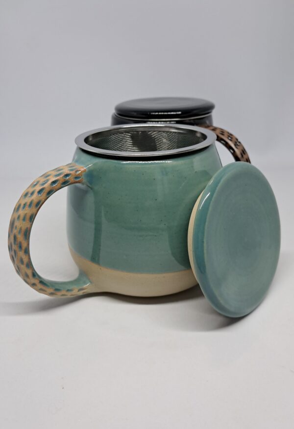 Mug tisanière bleu vert, présenté ouvert. Grès beige émaillé, anse décorée.